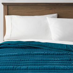 a bed with white pillows and blue quilted bedspread in a hotel room