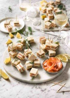 there are many small sandwiches on the plate with lemons and dill garnishes