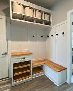 an empty room with white cabinets and wooden counter tops in the center, filled with baskets