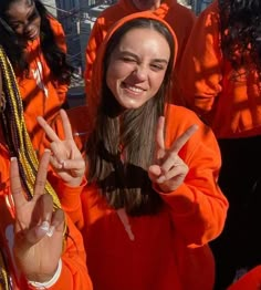 two girls in orange hoodies making the peace sign