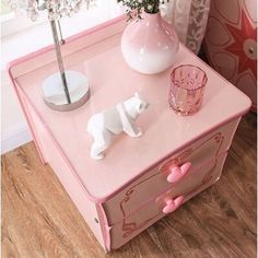 a pink table with a white dog figurine on top and flowers in the vase