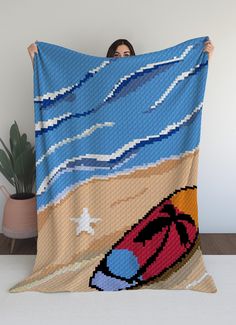 a woman is holding up a blanket with an image of a beach scene