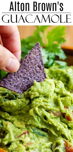 a hand dipping a tortilla chip into guacamole