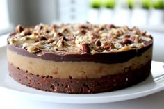 a chocolate cake with nuts on top sitting on a white plate