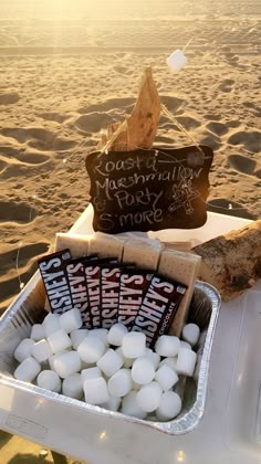 some marshmallows are in a tray on the beach