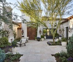 an outdoor courtyard with benches and potted trees