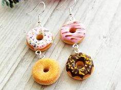 four donuts with sprinkles on them are hanging from silver earwires