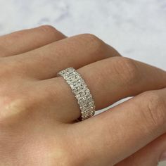 a woman's hand with a diamond ring on her left hand and the other hand holding it