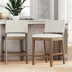 two white chairs sitting next to each other in front of a counter top with a potted plant on it