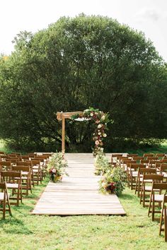 an outdoor ceremony set up with wooden chairs