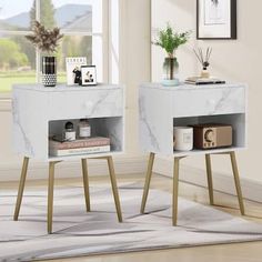 two white marble side tables with gold legs in front of a window and a rug on the floor