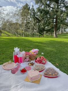 a picnic table with food and drinks on it in the middle of a grassy field