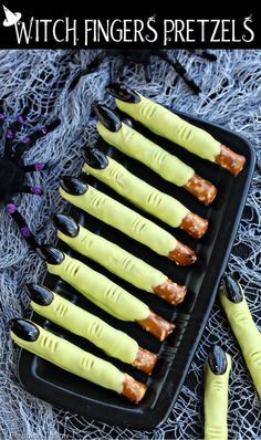 a tray filled with fake yellow and black fingernails next to a halloween decoration