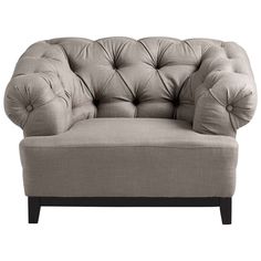 a beige chair with buttons on the back and arm rests against a gray background,