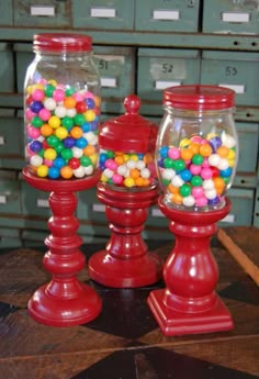 two glass jars filled with candy sitting on top of a wooden table next to each other