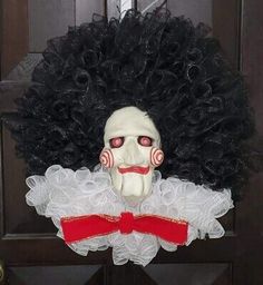 a creepy mask with curly hair and red eyes on top of a black door handle