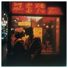 two people standing in front of a store window