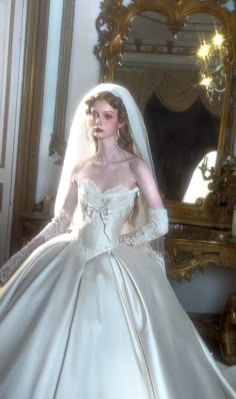 a woman in a white wedding dress standing next to a mirror