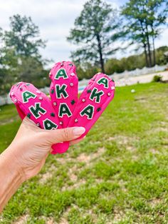 a person holding up a pink glove with letters on it