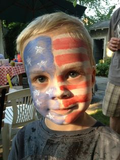 a young boy with his face painted in the colors of the united states and american flag