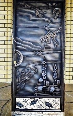 a metal door that is on the side of a brick building with flowers and birds