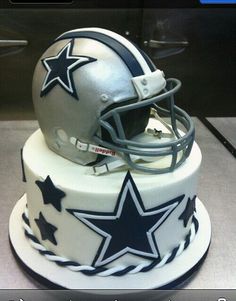 a cake with a football helmet on top and stars on the side is sitting on a table