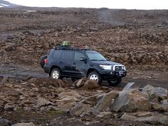 a black suv is driving through some rocks