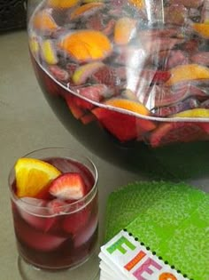 a bowl of fruit next to a glass of wine