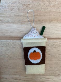 a felt coffee cup ornament hanging on a wooden table