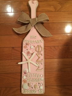 a pink bottle with a starfish and seashells on it sitting on a wooden floor