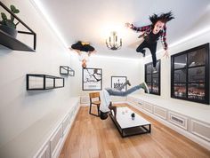 a person jumping in the air over a living room filled with furniture and pictures on the wall