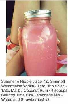 a pink drink in a glass jar sitting on top of a person's lap