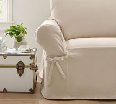 a living room with a white chair covered in a cover and a trunk next to it