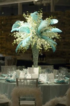 the centerpieces are decorated with feathers and white flowers, along with place settings