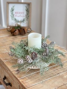 a wooden table topped with a candle and pine cones