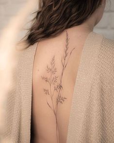 the back of a woman's neck with a small flower tattoo on her left shoulder