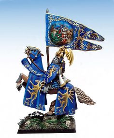 a figurine of a knight holding a blue flag and wearing armor with gold accents