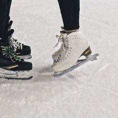 two people standing on skis in the snow with their feet propped against each other