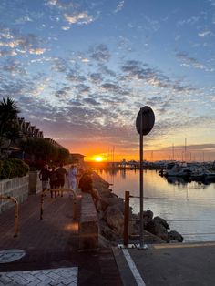 people are walking along the dock at sunset