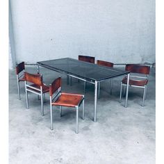 a table and four chairs in front of a white wall with concrete flooring on it