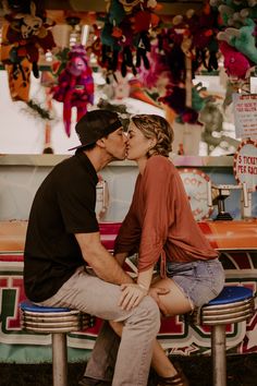 a man kissing a woman on the cheek in front of a food stand with decorations