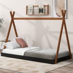 a bed with a wooden frame and white sheets in a room next to a plant