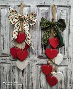 two red and white hearts hanging on the side of a wooden door with burlocks