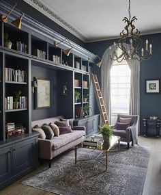 a living room with bookshelves, couches and a ladder hanging from the ceiling