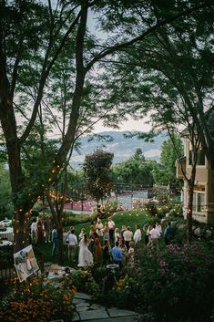 a group of people standing in front of a lush green forest filled with flowers and trees