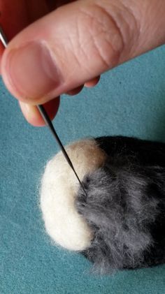 the needle is being used to thread up wool on a piece of felted material