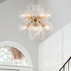 a chandelier hanging from the ceiling in a room with white walls and stairs