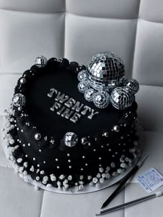 a black and white cake with silver decorations on it's top, next to a pair of scissors