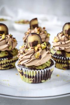 cupcakes with chocolate frosting and nuts are on a white plate, ready to be eaten