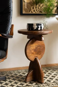 a wooden table sitting on top of a black and white rug next to a chair